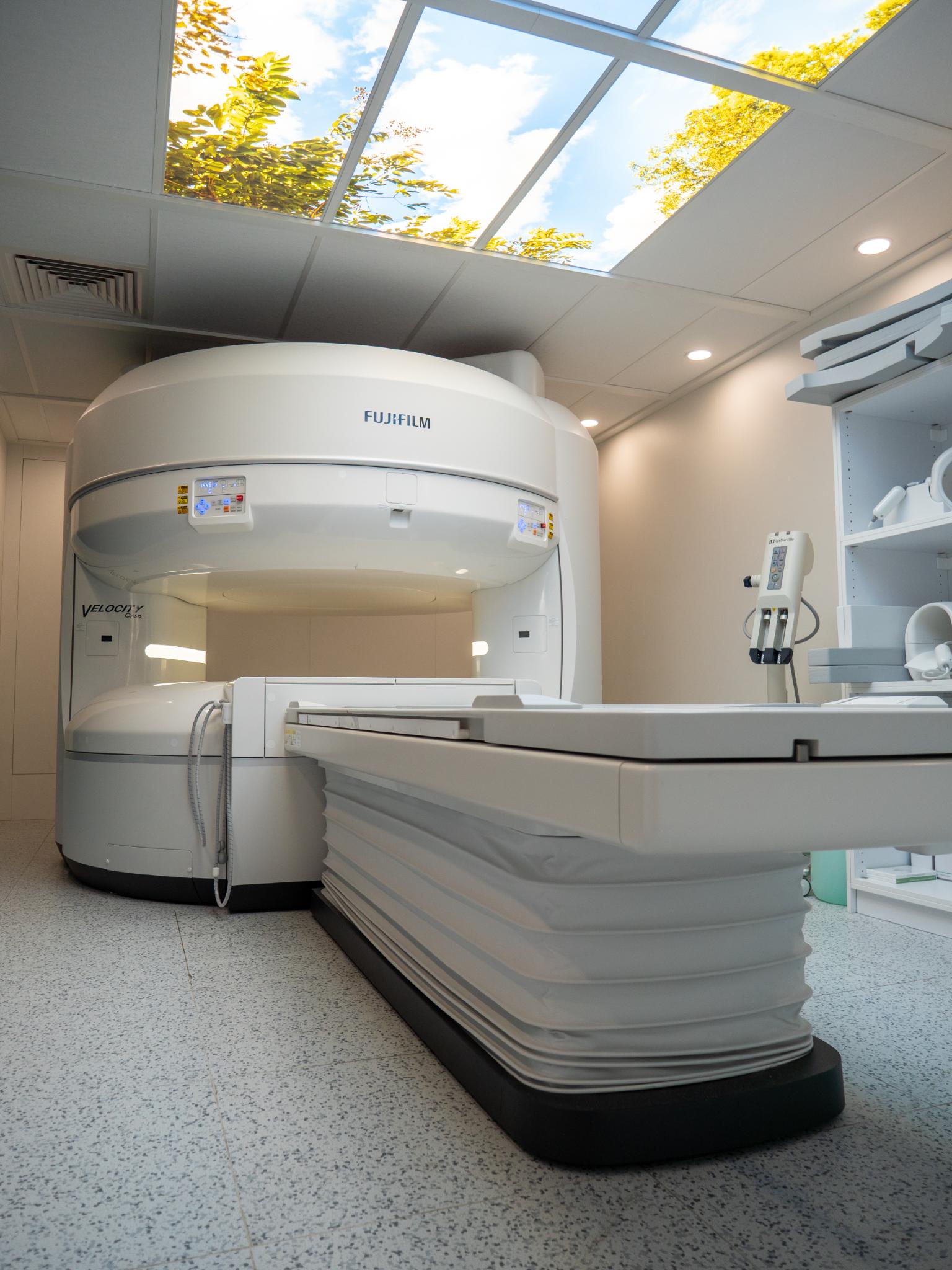 Sala de resonancia magnética pediátrica con tragaluz artificial de cielo y árboles para reducir el miedo y la ansiedad en niños.