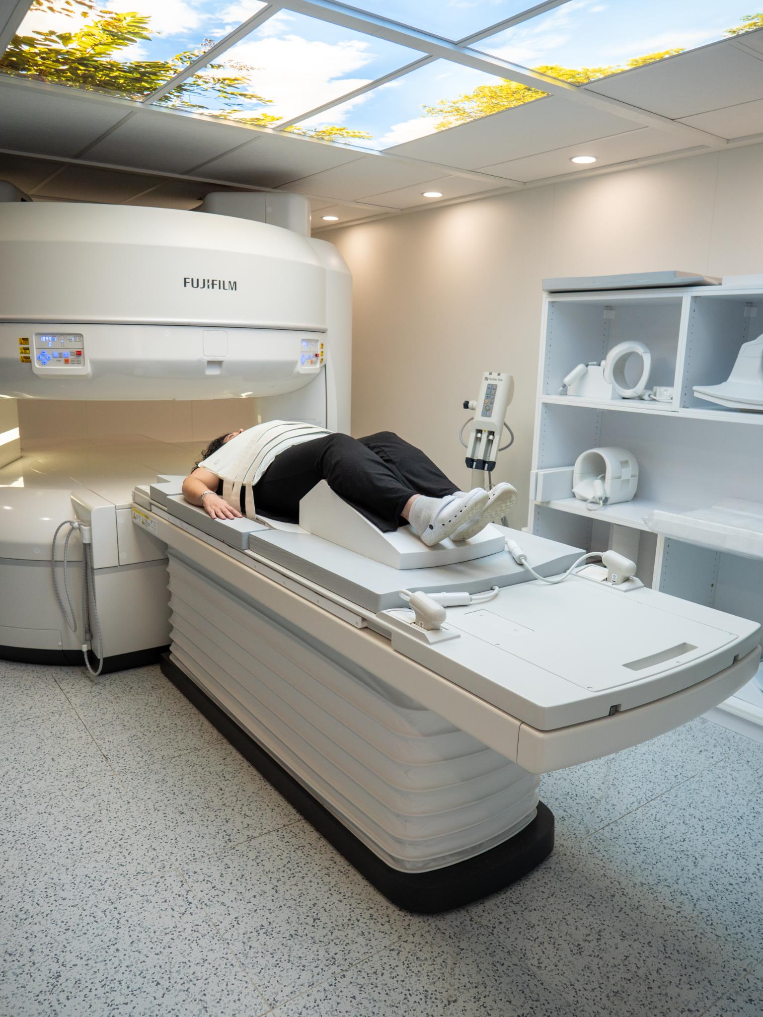 Paciente acostado en la camilla ancha de un equipo de resonancia magnética abierta Fujifilm Velocity Oasis, demostrando accesibilidad para movilidad reducida